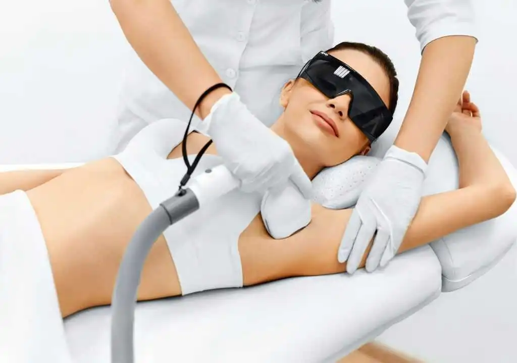 A patient undergoing laser hair removal treatment in a professional clinic setting. A trained technician uses a handheld laser device on the targeted area, illustrating a safe and advanced procedure designed for long-term hair reduction and smoother skin.